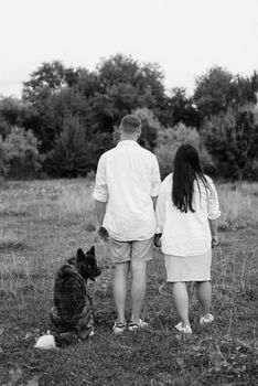 Big dog for a walk with a guy and a girl on the green prairie