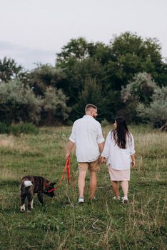 Big dog for a walk with a guy and a girl on the green prairie