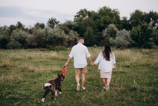 Big dog for a walk with a guy and a girl on the green prairie