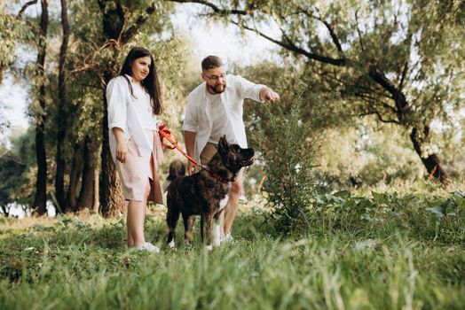 Big dog for a walk with a guy and a girl on the green prairie