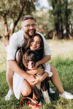 Big dog for a walk with a guy and a girl on the green prairie