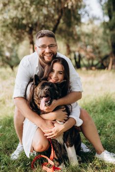 Big dog for a walk with a guy and a girl on the green prairie