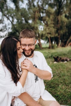 young couple in love a guy with a beard and a girl with dark hair in light clothes in the green forest