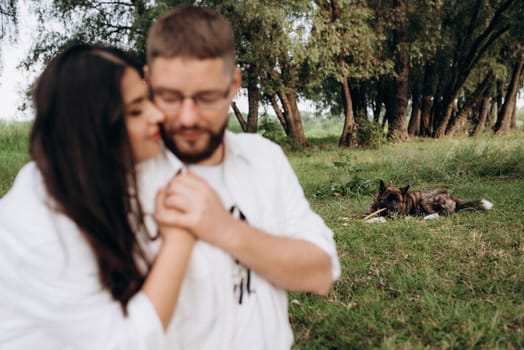 young couple in love a guy with a beard and a girl with dark hair in light clothes in the green forest