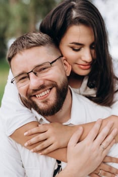 young couple in love a guy with a beard and a girl with dark hair in light clothes in the green forest