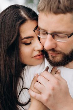 young couple in love a guy with a beard and a girl with dark hair in light clothes in the green forest