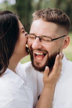 young couple in love a guy with a beard and a girl with dark hair in light clothes in the green forest