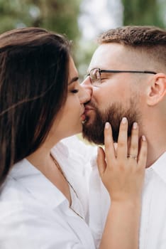 young couple in love a guy with a beard and a girl with dark hair in light clothes in the green forest