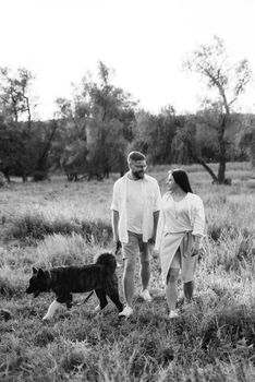 Big dog for a walk with a guy and a girl on the green prairie