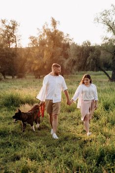 Big dog for a walk with a guy and a girl on the green prairie