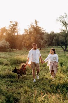 Big dog for a walk with a guy and a girl on the green prairie