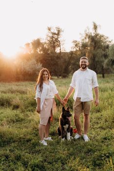 Big dog for a walk with a guy and a girl on the green prairie