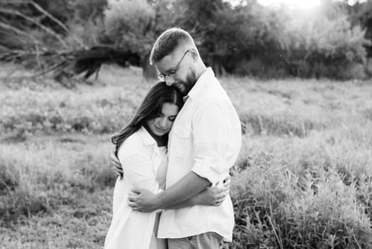 young couple in love a guy with a beard and a girl with dark hair in light clothes in the green forest