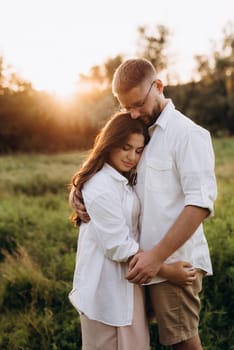 young couple in love a guy with a beard and a girl with dark hair in light clothes in the green forest