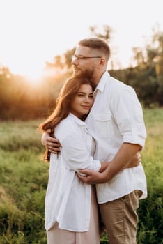 young couple in love a guy with a beard and a girl with dark hair in light clothes in the green forest