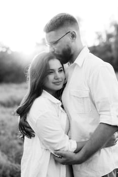 young couple in love a guy with a beard and a girl with dark hair in light clothes in the green forest