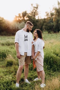 young couple in love a guy with a beard and a girl with dark hair in light clothes in the green forest