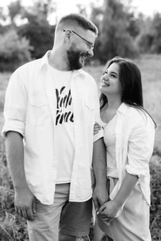 young couple in love a guy with a beard and a girl with dark hair in light clothes in the green forest