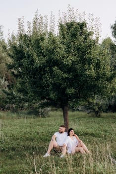 young couple in love a guy with a beard and a girl with dark hair in light clothes in the green forest