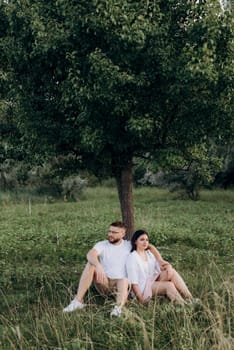 young couple in love a guy with a beard and a girl with dark hair in light clothes in the green forest