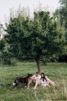 Big dog for a walk with a guy and a girl on the green prairie