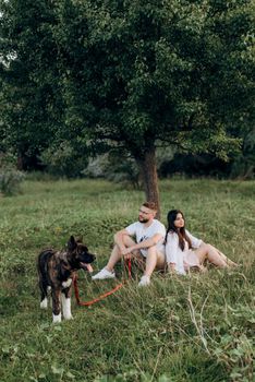 Big dog for a walk with a guy and a girl on the green prairie