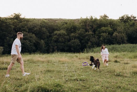 Big dog for a walk with a guy and a girl on the green prairie