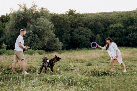 Big dog for a walk with a guy and a girl on the green prairie