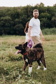 Big dog for a walk with a guy and a girl on the green prairie