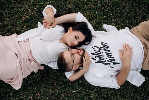 young couple in love a guy with a beard and a girl with dark hair in light clothes in the green forest