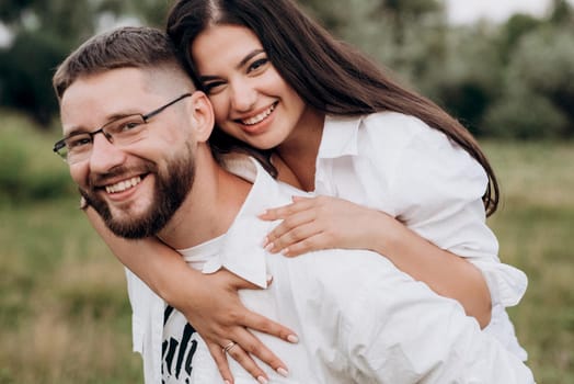 young couple in love a guy with a beard and a girl with dark hair in light clothes in the green forest