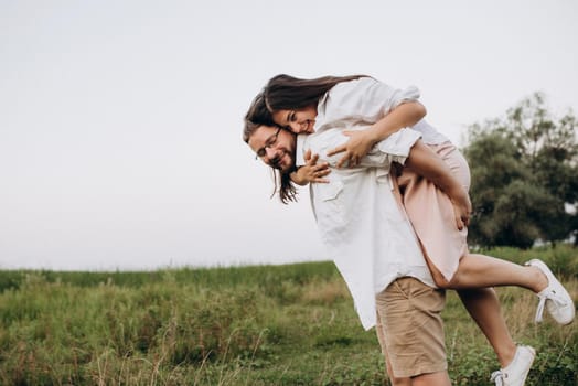 young couple in love a guy with a beard and a girl with dark hair in light clothes in the green forest