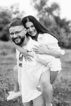 young couple in love a guy with a beard and a girl with dark hair in light clothes in the green forest