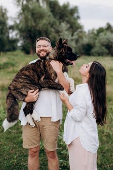 Big dog for a walk with a guy and a girl on the green prairie