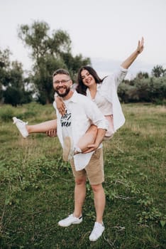 young couple in love a guy with a beard and a girl with dark hair in light clothes in the green forest