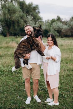 Big dog for a walk with a guy and a girl on the green prairie