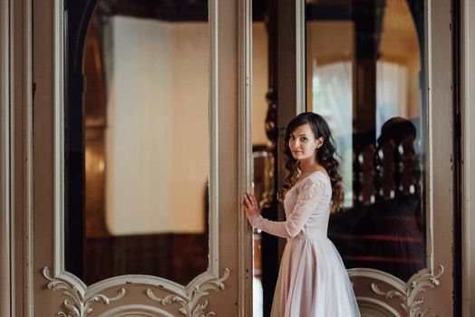 A girl in a light pink dress against the background of a medieval Polish stone castle