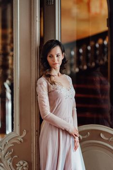 A girl in a light pink dress against the background of a medieval Polish stone castle