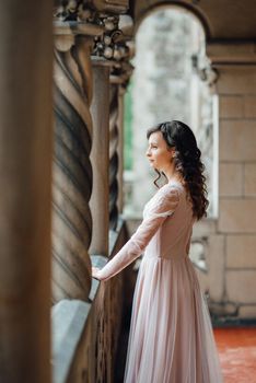 A girl in a light pink dress against the background of a medieval Polish stone castle