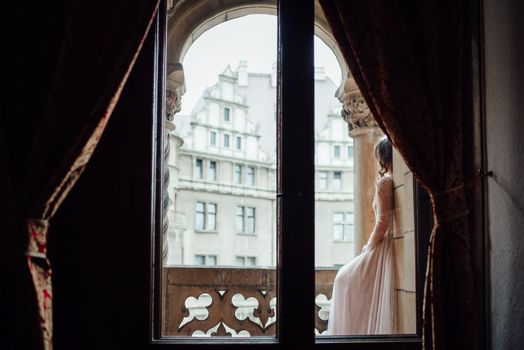 A girl in a light pink dress against the background of a medieval Polish stone castle