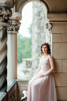 A girl in a light pink dress against the background of a medieval Polish stone castle