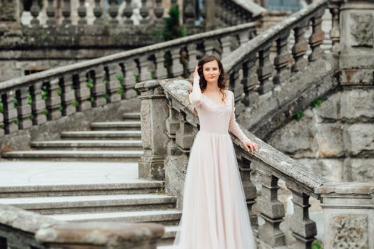 A girl in a light pink dress against the background of a medieval Polish stone castle