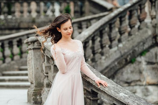 A girl in a light pink dress against the background of a medieval Polish stone castle