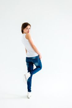 cheerful girl in a white t-shirt and dark blue jeans in the studio on a white background stands, sits, runs