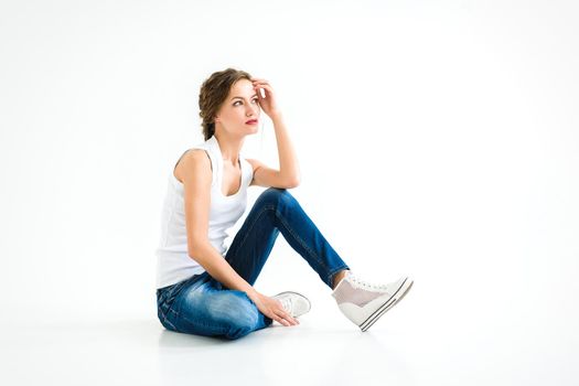 cheerful girl in a white t-shirt and dark blue jeans in the studio on a white background stands, sits, runs