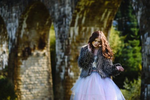 the bride walks under a bridge in a fur Cape in the Carpathians