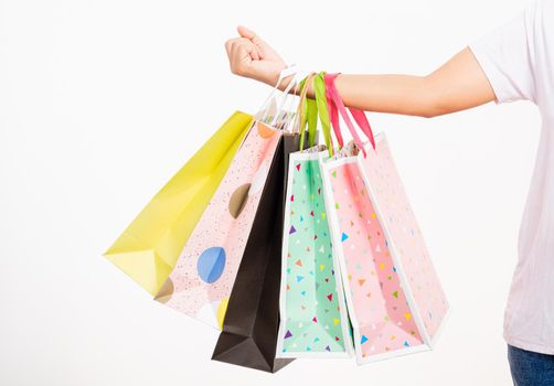 Closeup women hand holding colorful multicolor shopping bag many packets isolated on white background, female holds in hand white clear empty blank craft paper gift bag, shopping day concept