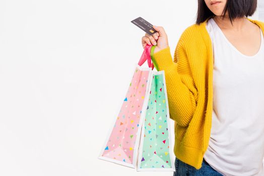 Happy woman hand she wears yellow shirt holding shopping bags multicolor and credit card, young female hold many packets within arms isolated on white background, Black Friday sale concept