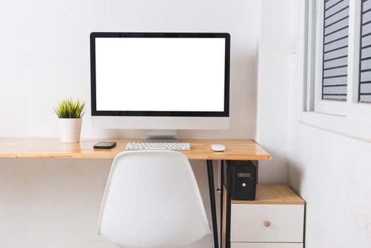 Computer monitor with white blank screen on the business desk with wireless mouse, keyboard at home office over white wall background, Photo of equipment contemporary workspace