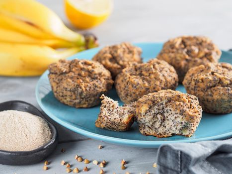 Close-up view of healthy gluten-free homemmade banana muffins with buckwheat flour. Vegan muffins with poppy seeds on blue plate over gray wooden table. Copy space
